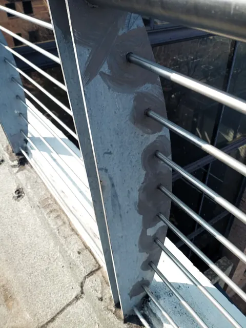 Steel balustrade post with grey primer patches over rust spots