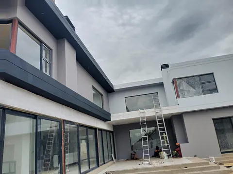 New double-storey house with ladders up during exterior painting