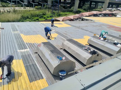 MP crew on a factory roof applying coating around the roof vents