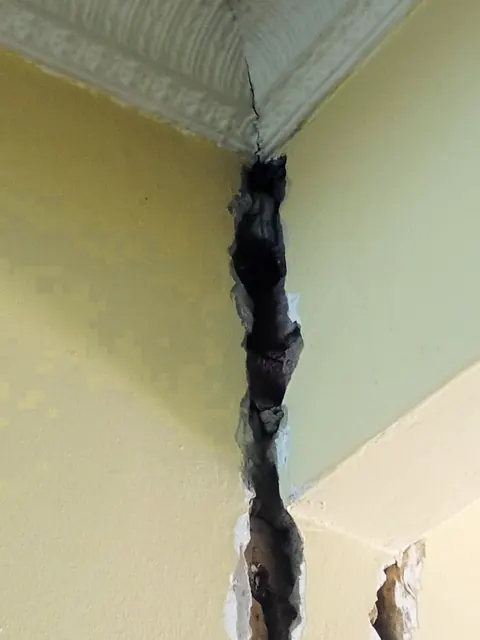 Wide crack in a plaster wall, opened up ready for repair