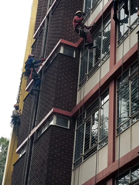 MP technicians working down the face of a brick high-rise on ropes